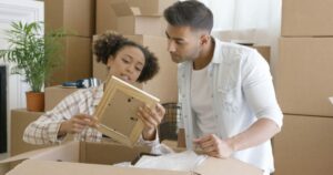 Discover practical packing tips with our guide as a couple efficiently organizes their belongings into moving boxes, ensuring a smooth relocation.